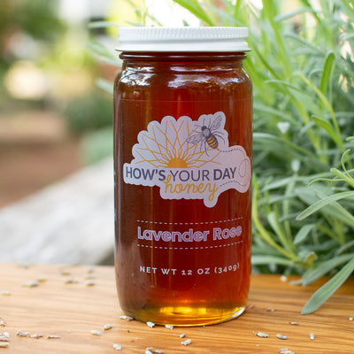 Raw local lavender rose infused honey from How's Your Day Honey in St. Petersburg FL, one 12oz jar. Photographed on a cutting board with lavender flowers..